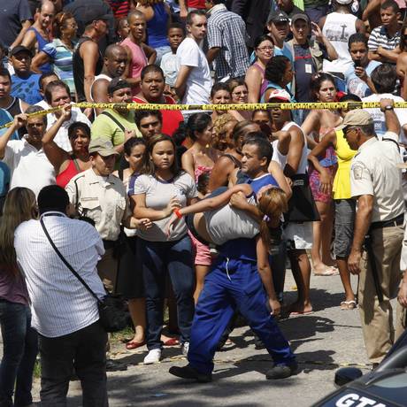 Massacre. Uma aluna da Escola Municipal Tasso da Silveira é carregada após a morte de 12 jovens Foto: Wania Corredo 07/04/2011 / Agência O Globo