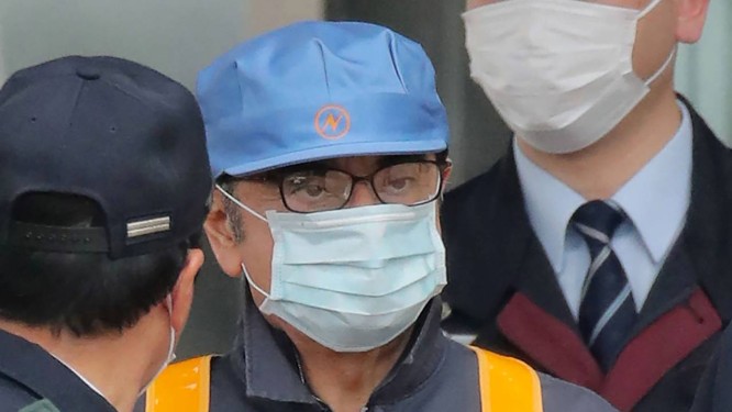 De bonÃ© azul e mÃ¡scara cirÃºrgica, Ghosn deixa a prisÃ£o. Ele Ã© acusado de fraude fiscal Foto: JIJI PRESS / AFP