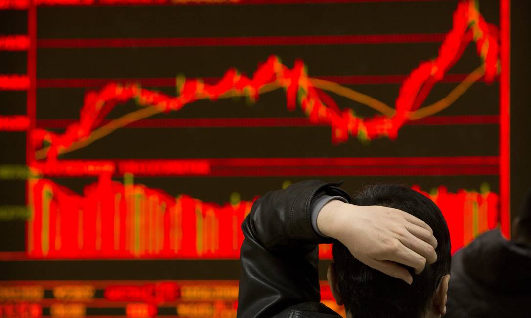 Investidor acompanha oscilação das ações em corretora de Pequim. Bolsas da China e de Hong Kong fecharam em queda, após surto de Covid em Shenzen Foto: Mark Schiefelbein / AP