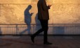 Homem caminha usando um smartphone na Canary Wharf, distrito financeiro de Londres
