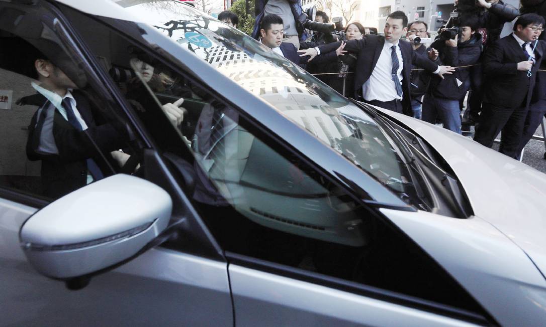 Carro, supostamente levando Carlos Ghosn de volta à prisão, deixa a casa do executivo Foto: JIJI PRESS / AFP