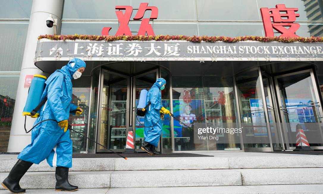 Equipes médicas jogam spray antisséptico na principal entrada da Bolsa de Xangai Foto: Yifan Ding / Getty Images