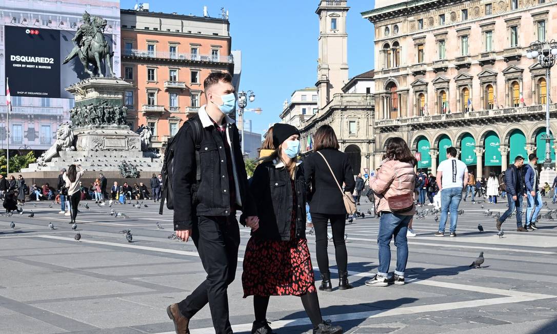 Casal caminha pela Praça da Catedral (Milão) vestindo máscaras cirúrgicas em meio ao surto de coronavírus na região Foto: Andreas Solaro / AFP