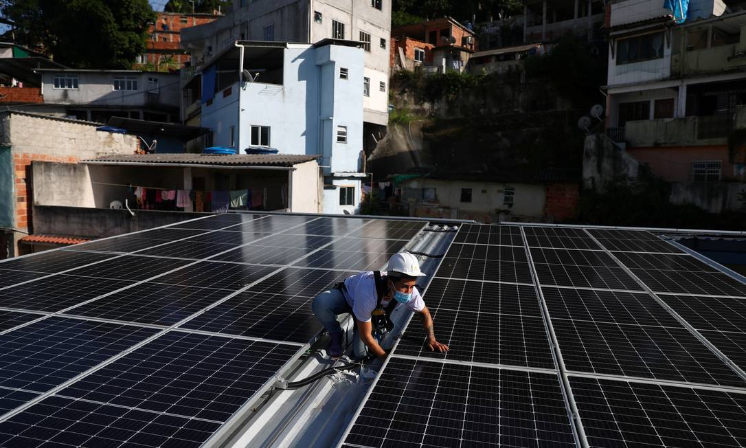 Painel solar sendo instalado no telhado da Associação dos moradores da Babilônia, no Rio Foto: PILAR OLIVARES / Reuters
