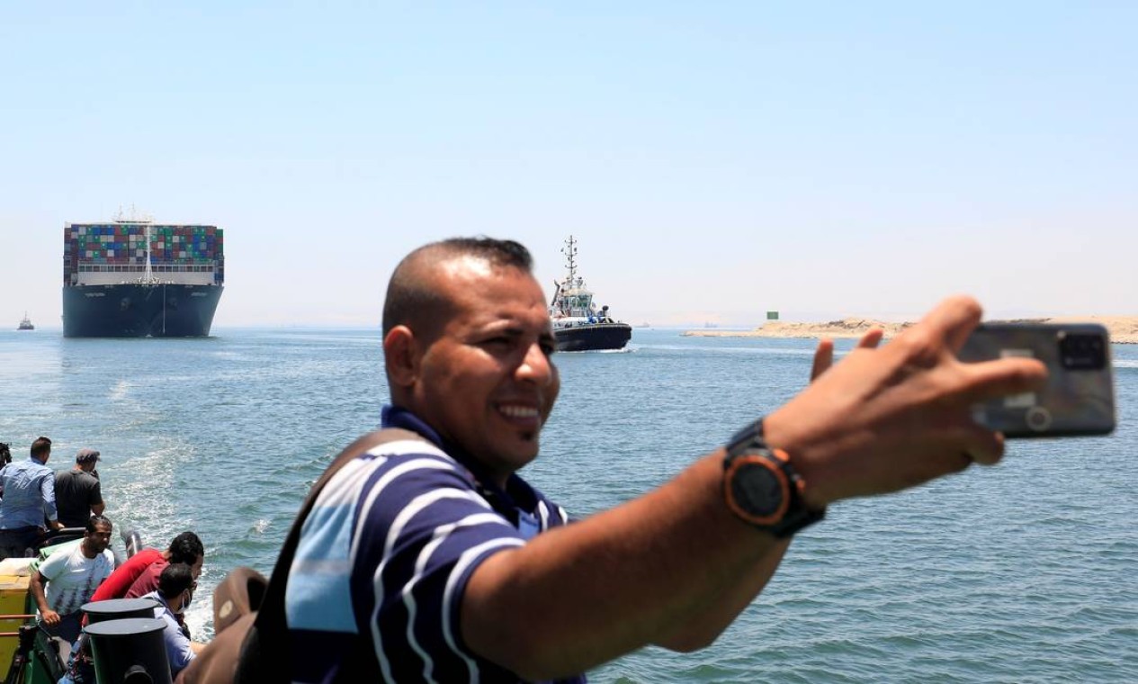 Um homem tira uma selfie tendo ao fundo o Ever Given que começou a zarpar para partir depois de quase quatro meses estacionado no Canal de Suezque, a rota marítima mais curta entre a Europa e a Ásia. Foto: AMR ABDALLAH DALSH / REUTERS