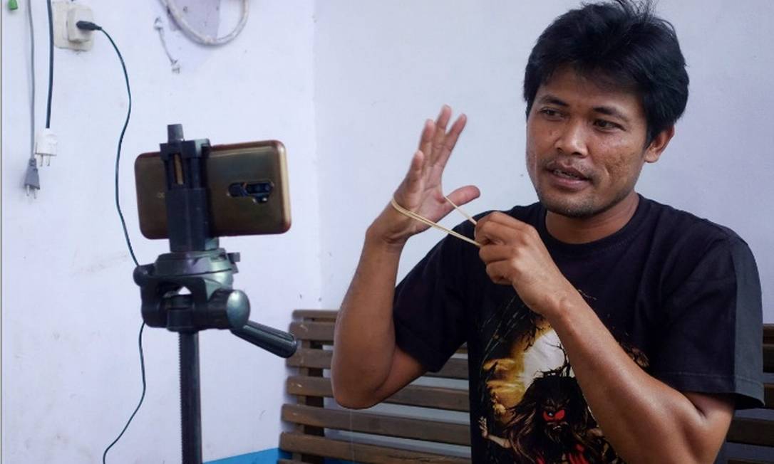 O mecânico indonésio Siswanto grava um de seus vídeos em sua casa, na comunidade agrícola em Banyuwangi Foto: Arbi Anugerah/AFP