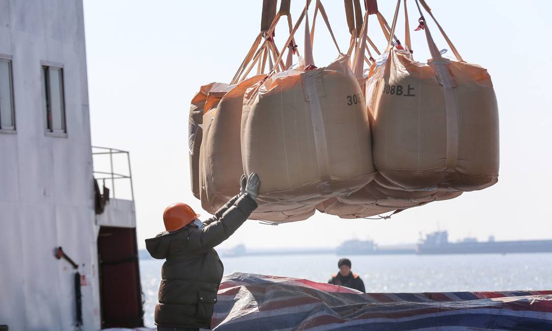 Um trabalhador com máscara protetora transfere sacos de fertilizante químico a serem exportados em um porto em Nantong, na província de Jiangsu, no leste da China, durante o surto do vírus na cidade de Wuhan, em Hubei Foto: STR / STR/AFP
