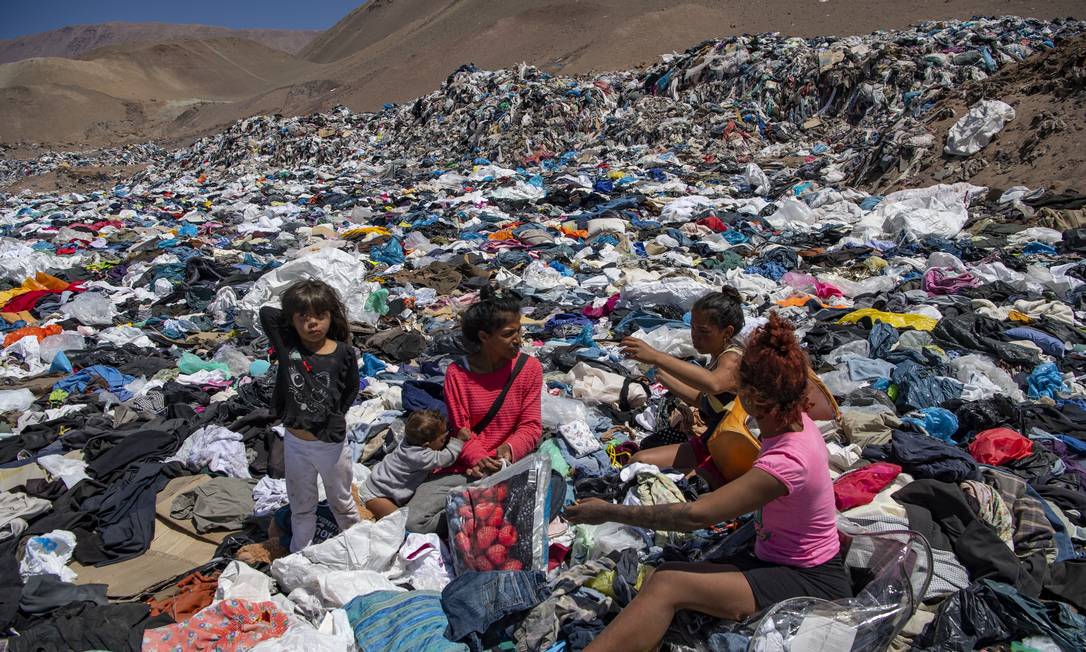 Mulheres &#039;garimpam&#039; roupas em meio a toneladas descartadas no deserto do Atcama, no Chile Foto: MARTIN BERNETTI / AFP