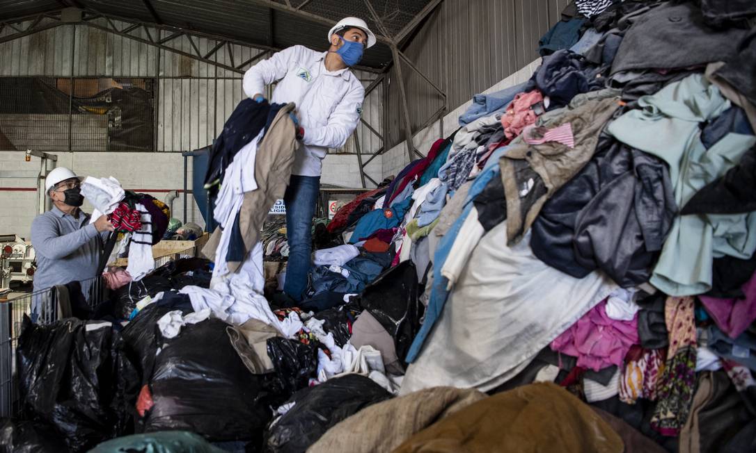 Homem trabalha em uma fábrica que recicla roupas usadas descartadas no deserto do Atacama Foto: MARTIN BERNETTI / AFP