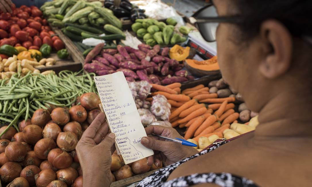 Sonia Maria Santos anota itens para comparar preços na feira. Tomate, mais caro, ficou de fora da lista Foto: Guito Moreto / Agência O Globo
