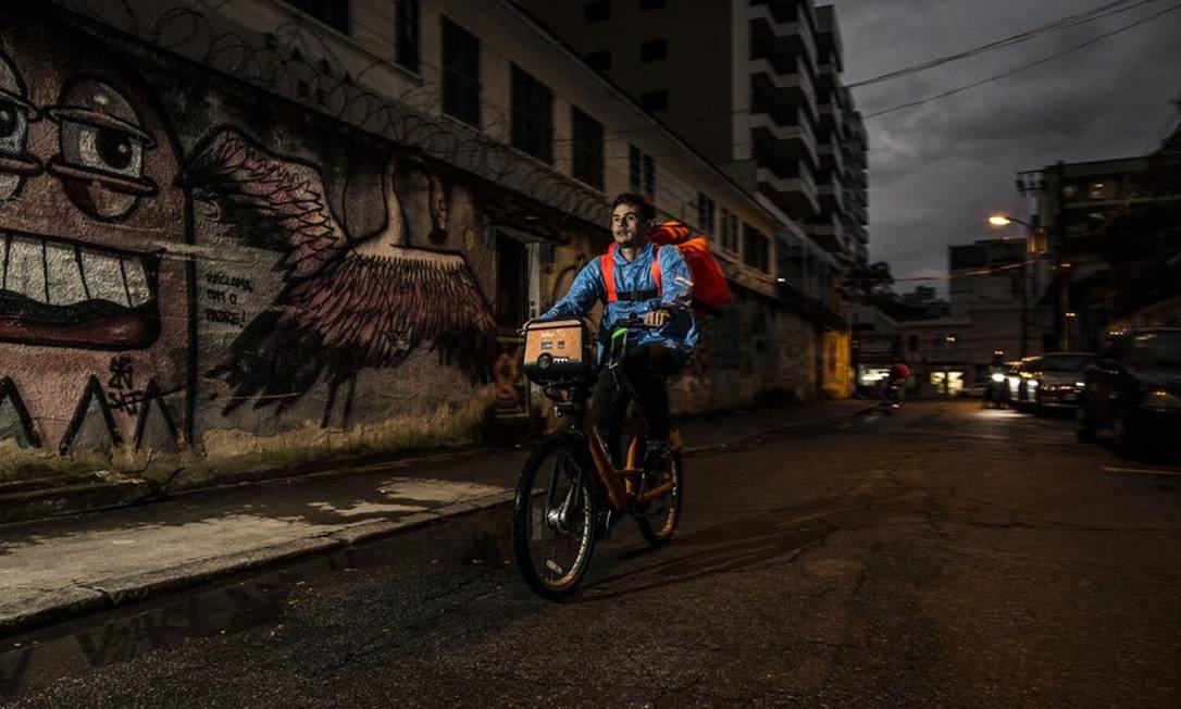O venezuelano Daniel Rabón, que vende passeios no calçadão de Copacabana, no Rio de Janeiro, durante a manhã e roda a cidade como entregador de aplicativo à tarde e à noite. Foto: Guito Moreto / Agência O Globo