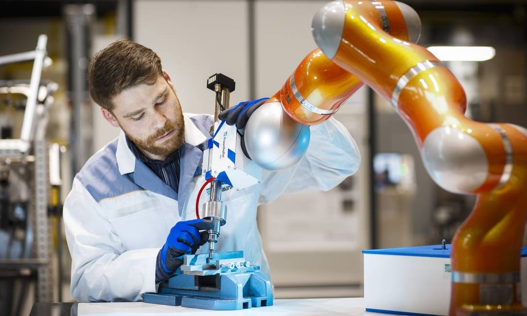 Um empregado ajusta o tamanho de um braço de um robô no centro de pesquisa de uma fábrica em Chemnitz, na Alemanha. A robotização desenfreada tem sido revista em empresas como a Boeing. Foto: Ute Grabowsky / Photothek / Getty Images