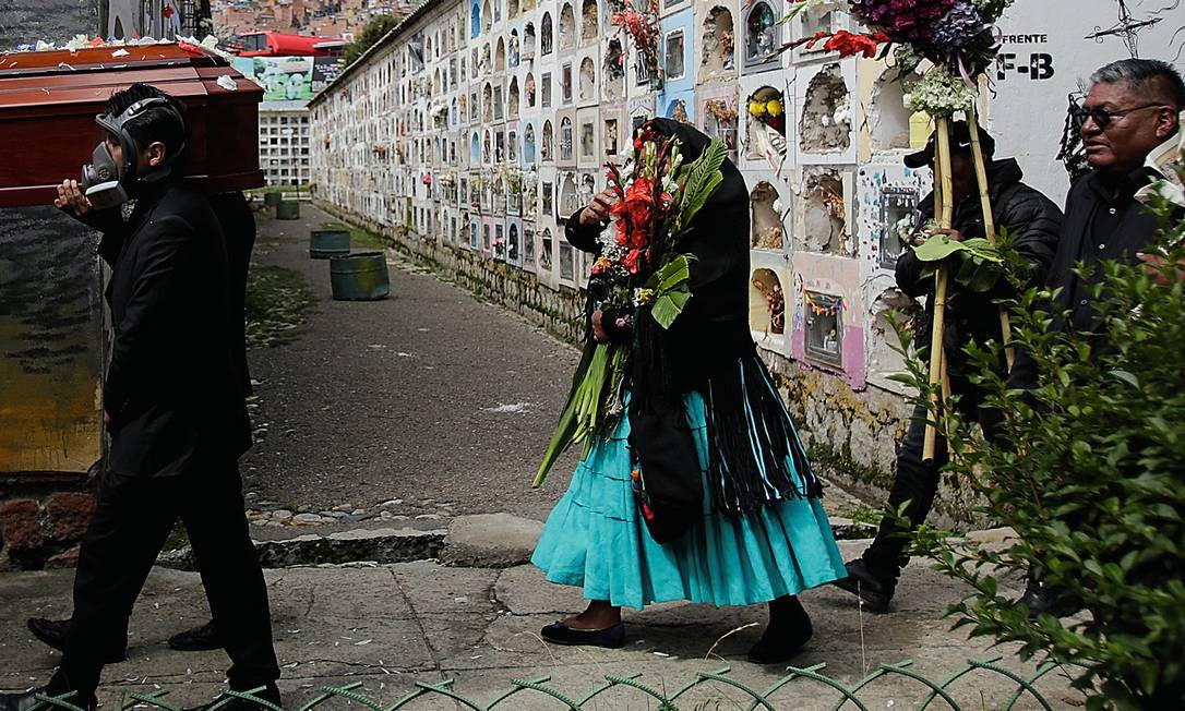 A doença se espalhou pelo planeta. Num enterro na Bolívia, o caixão é carregado por pessoas protegidas por máscaras. Foto: David Mercado / Reuters