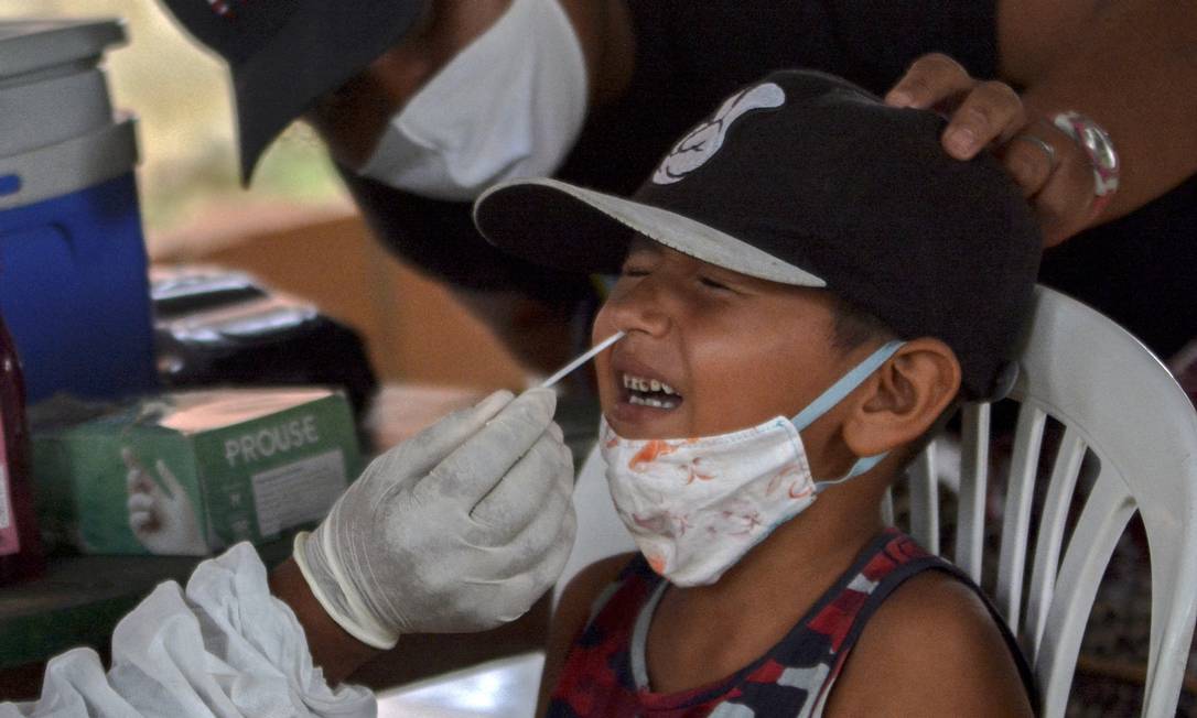 Um profissional de saúde coleta uma amostra de uma criança para realizar um teste de Covid-19 na comunidade ribeirinha de Bela Vista do Jaraqui, em Manaus. Foto: Marcio James / AFP