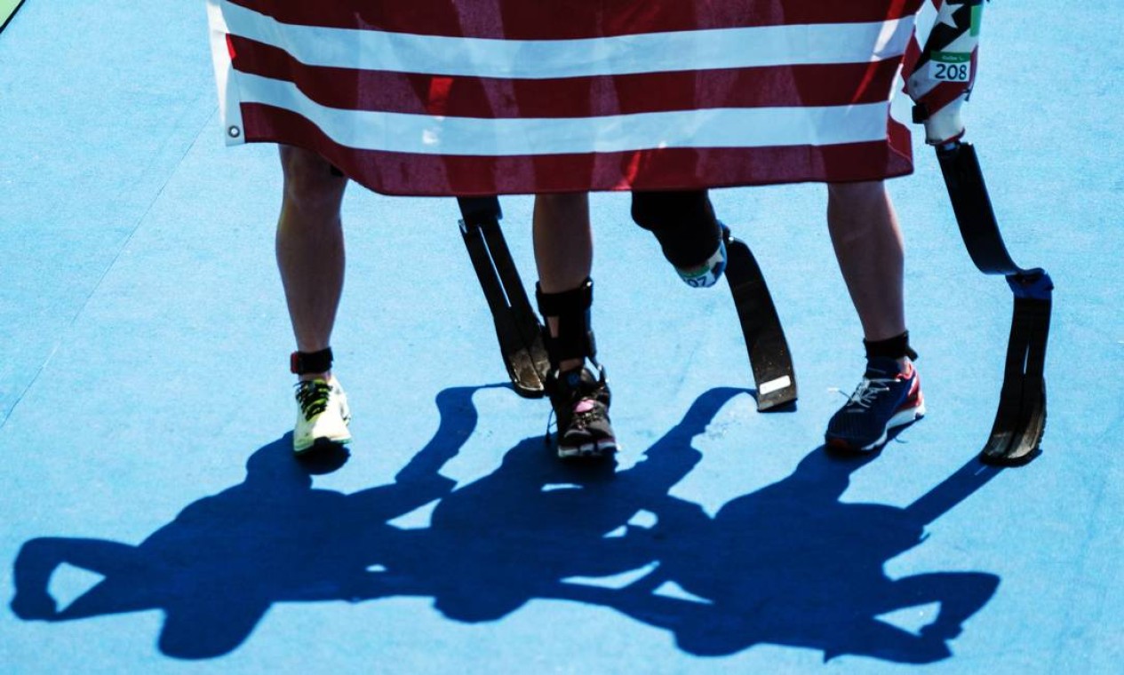 As americanas Allysa Seely, Hailey Danisewicz e Melissa Stockwell posam com a bandeira de seu país durante o triatlo Foto: YASUYOSHI CHIBA / AFP