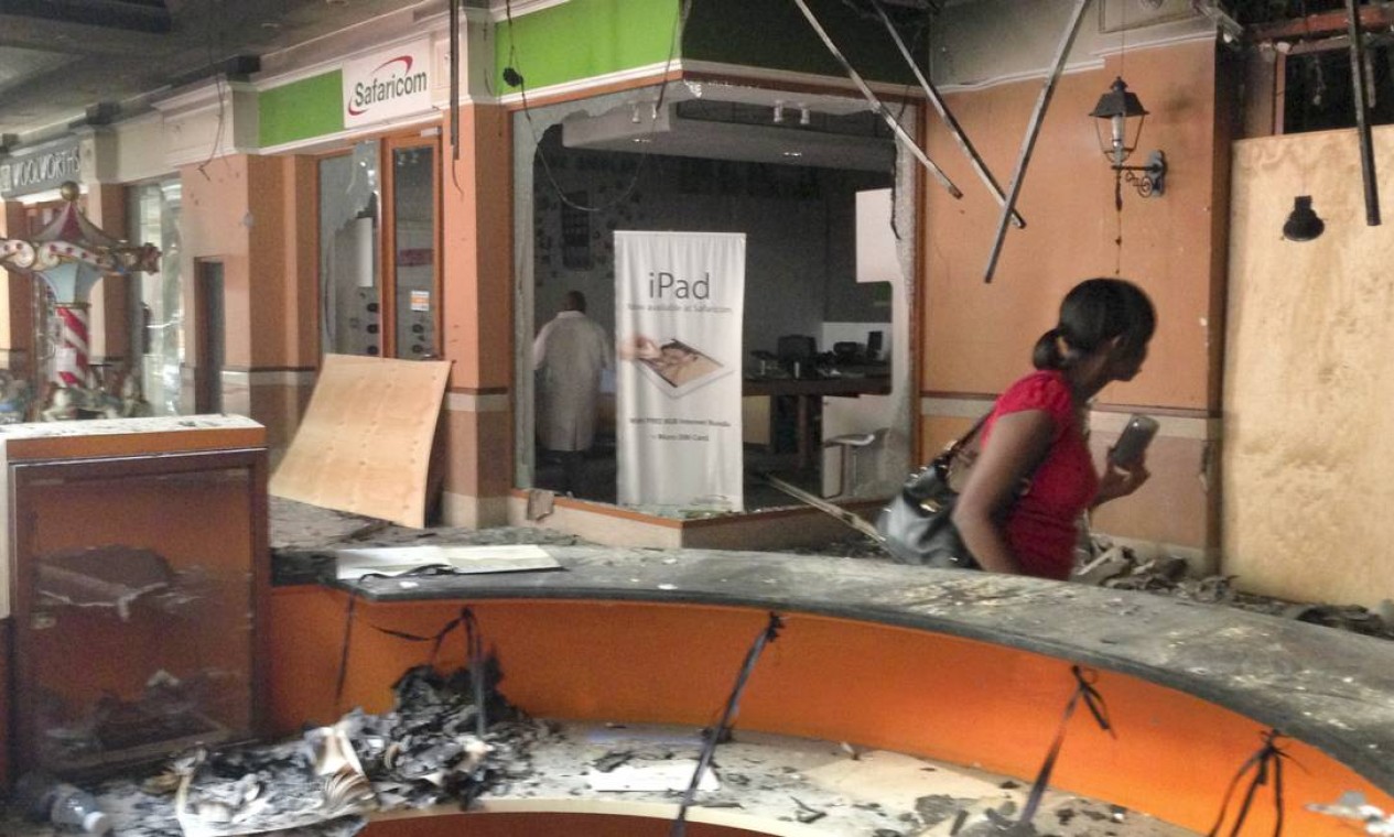 Uma mulher passa diante de uma loja de celulares destruída Foto: Jason Straziuso / AP