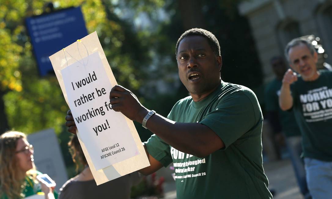 Funcionário licenciado pelo governo americano protesta: "Eu preferia estar trabalhando para você" Foto: WIN MCNAMEE / AFP