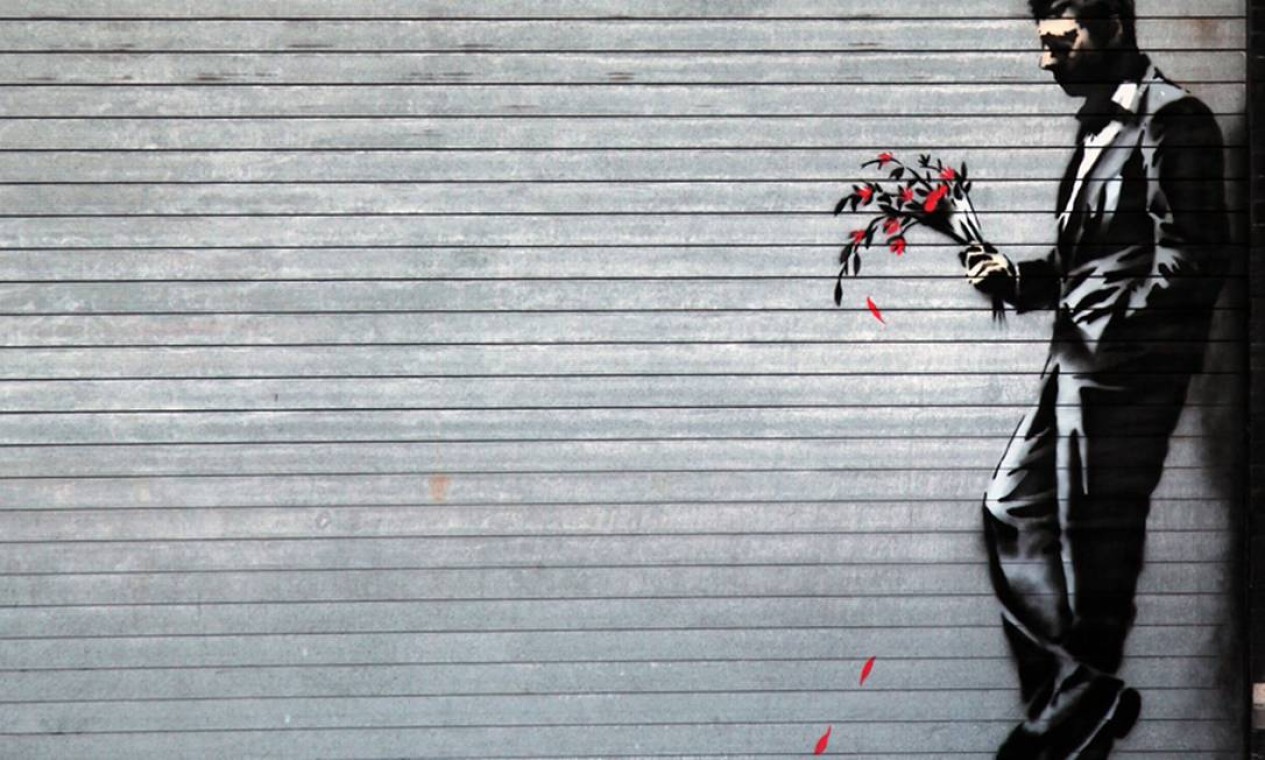 Um homem engravatado segurando um buquê de flores foi incrustado na porta da garagem da casa noturna Hustler. Em seu site, Banksy descreveu o desenho: 'Esperando em vão na porta da boate' Foto: Divulgação