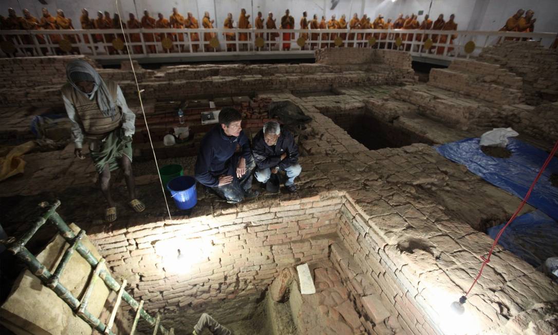 
Arqueólogos Robin Coningham e Kosh Prasad Acharya nas escavações do templo Maya Devi; ao fundo monges tailandeses meditam.
Foto: National Geographic / Ira Block