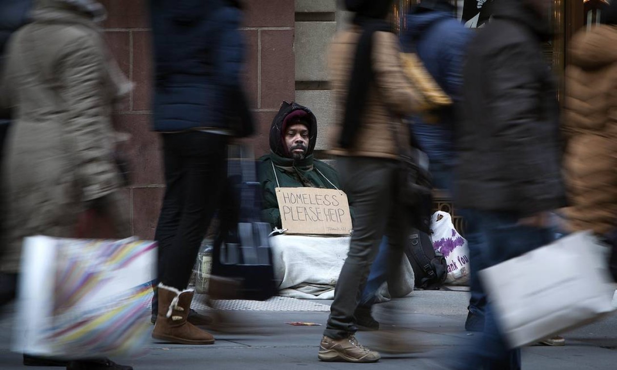 Um homem sem-teto, observa o movimento de consumidores durante a Black Friday, em Nova York Foto: CARLO ALLEGRI / REUTERS