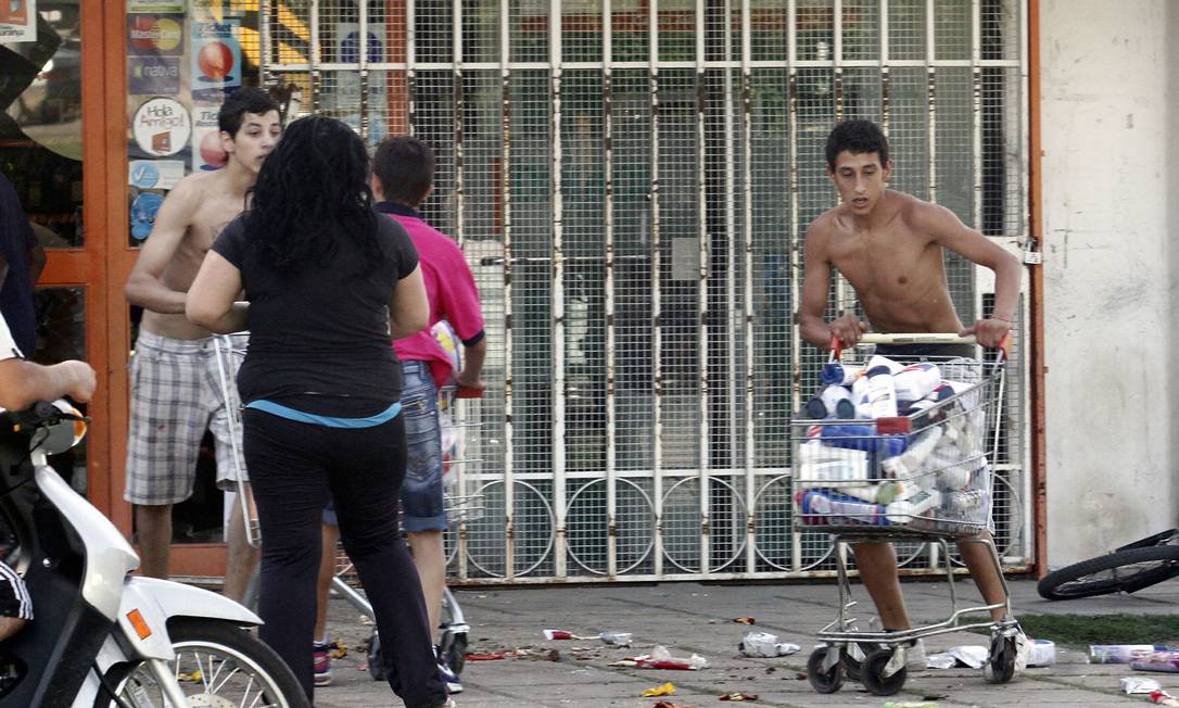 
Saqueadores deixam um supermercado em Córdoba, na Argentina. Distúrbios deixaram um jovem morto
Foto: AFP