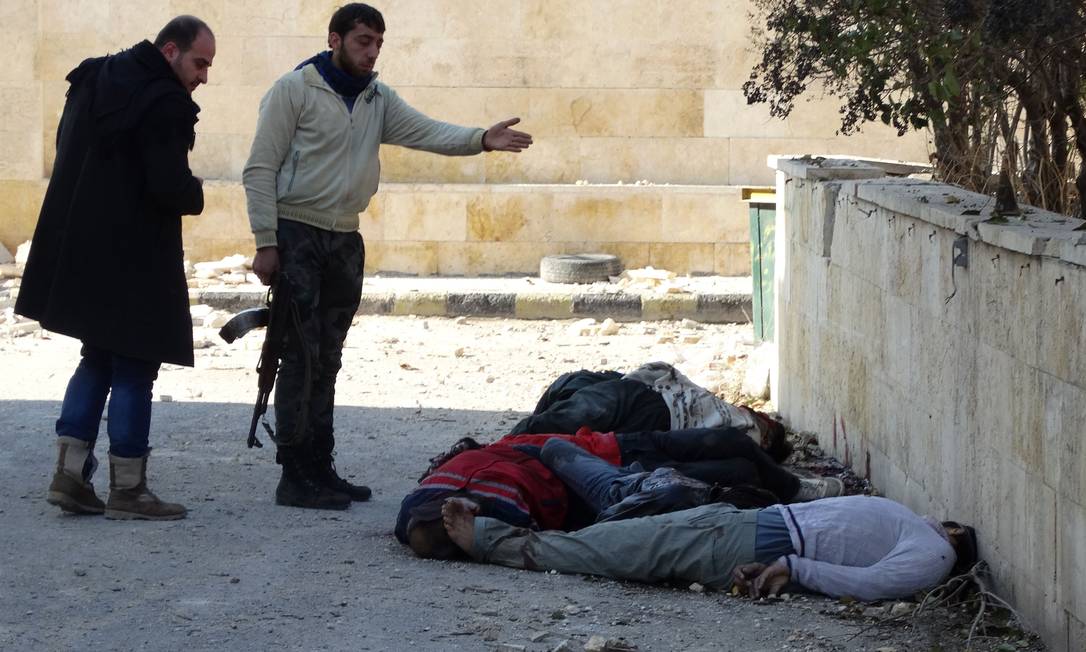 
Rebeldes do Isis gesticulam ao encontrar corpos vendados e algemados em Aleppo
Foto: MAHMUD AL-HALABI / AFP
