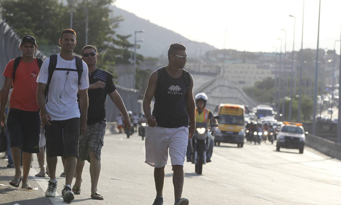 Pessoas caminham pela Linha Amarela interditada: invasão da pista atrasou reabertura da via Foto: Domingos Peixoto / Agência O Globo