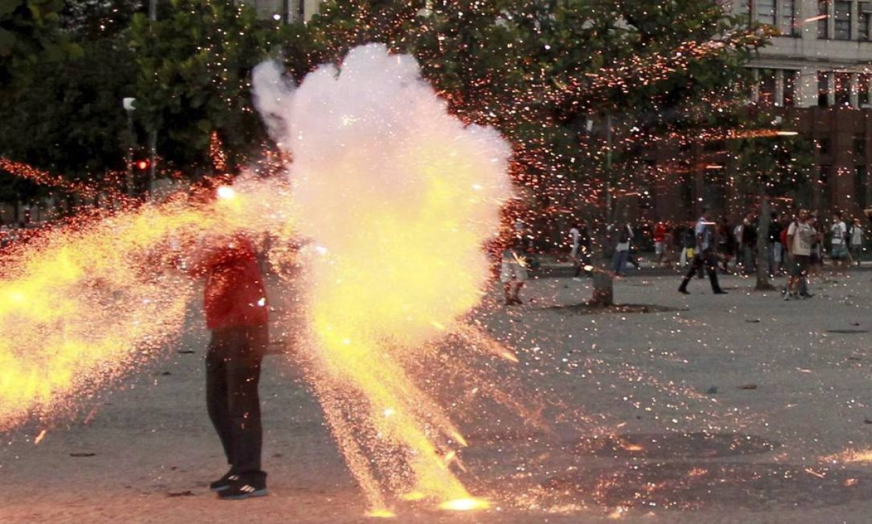 O cinegrafista é cercado pelo fogo de explosivo: artefato foi atirado durante protesto no Centro Foto: Agência O Globo
