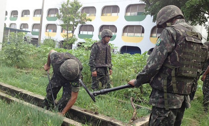Soldados do Exército procuram armas na horta num Ciep, no Complexo da Maré Foto: Marcia Foletto / Agência O Globo