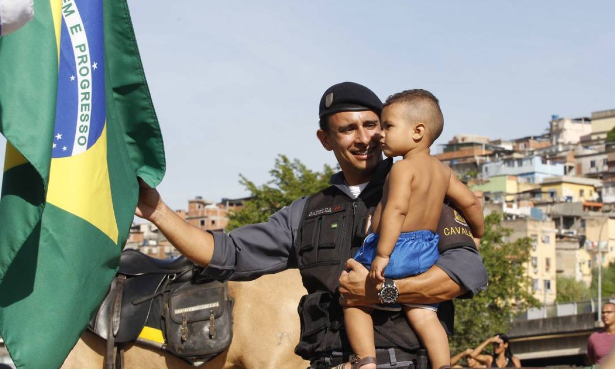 Policial mostra a bandeira do Brasil para o pequeno morador do Complexo da Maré Foto: Pablo Jacob / Agência O Globo