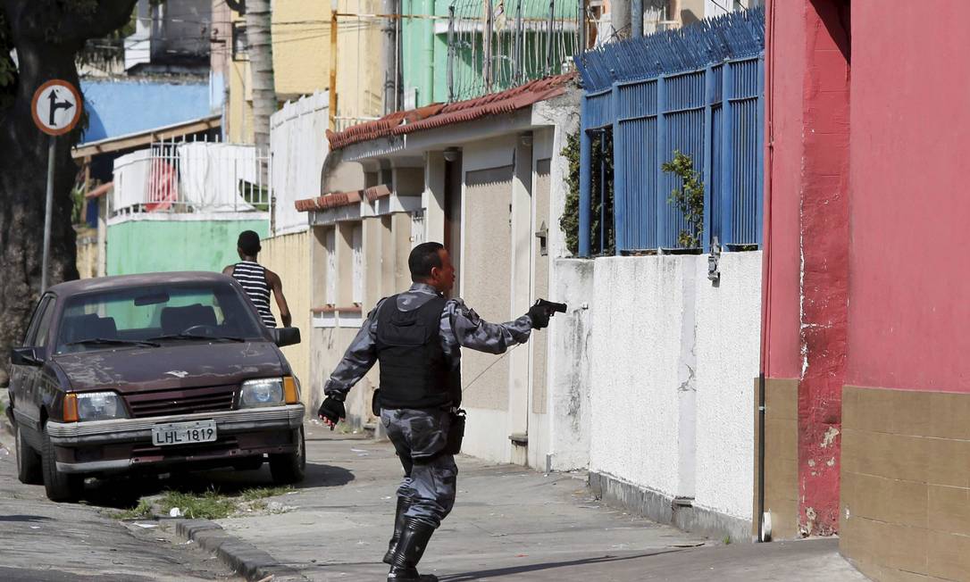 Policial aponta arma para beco no entorno da Favela da Oi Foto: Pablo Jacob / Agência O Globo
