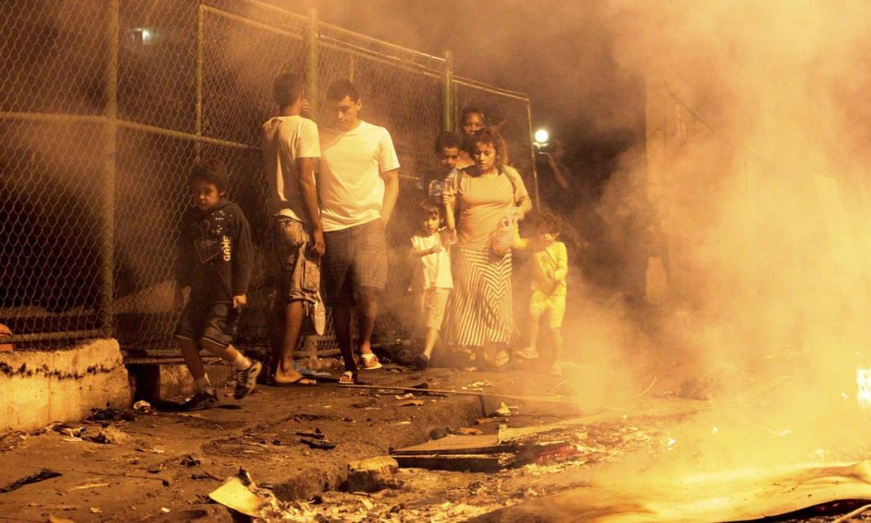 Moradores passam pela rua cheia de fumaça Foto: Marcelo Piu / Agência O Globo
