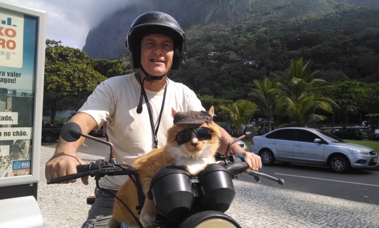 Alexandre coloca Chiquinho, equipado com óculos e boné, sobre a moto e parte para a praia para a caminhada rotineira Foto: Fabíola Leoni / O Globo