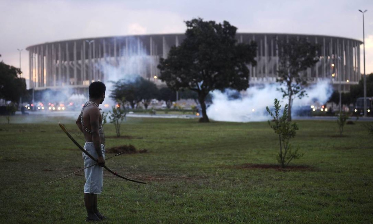 A native Brazilian stands in front of the Mane Garrincha soccer stadium as police use tear gas to impede a group of Indians from approaching it during a demonstration in Brasilia, May 27, 2014. Police fired tear gas canisters to contain anti-World Cup demonstrators who tried to march to the Brasilia stadium where the soccer tournament's trophy was on public display on Tuesday. REUTERS/Lunae Parracho (BRAZIL - Tags: SPORT SOCCER WORLD CUP CIVIL UNREST POLITICS TPX IMAGES OF THE DAY) Foto: LUNAE PARRACHO / REUTERS