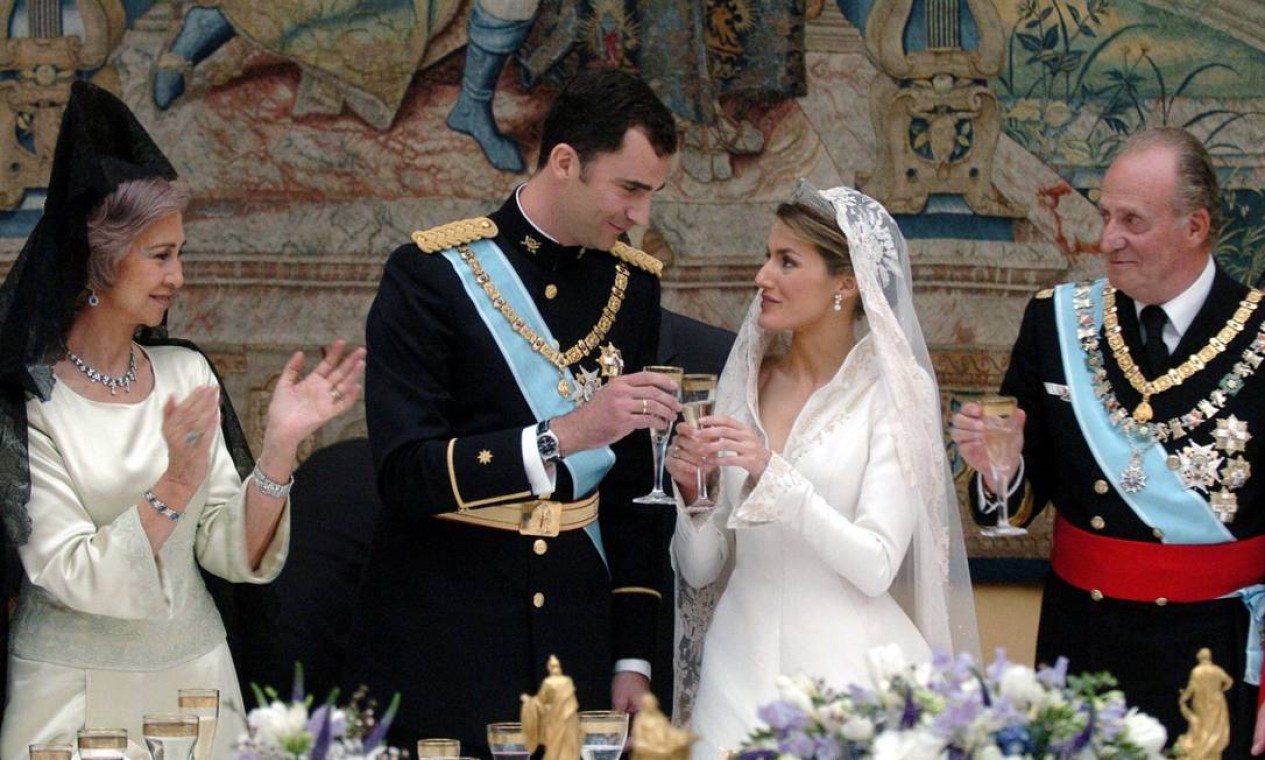O rei Juan Carlos (à direita) celebra o casamento do filho, o príncipe Felipe de Bourbon (ao centro), com Letizia Ortiz, em maio de 2004. A recepção aconteceu no Palácio Real, em Madri Foto: BALLESTEROS / AFP
