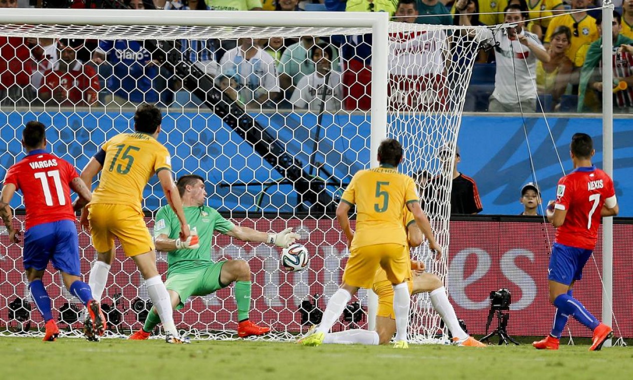 Momento do primeiro gol do Chile. Alexis Sanchez chuta, a bola desvia na zaga e engana o goleiro da Austrália Foto: Frank Augstein / AP