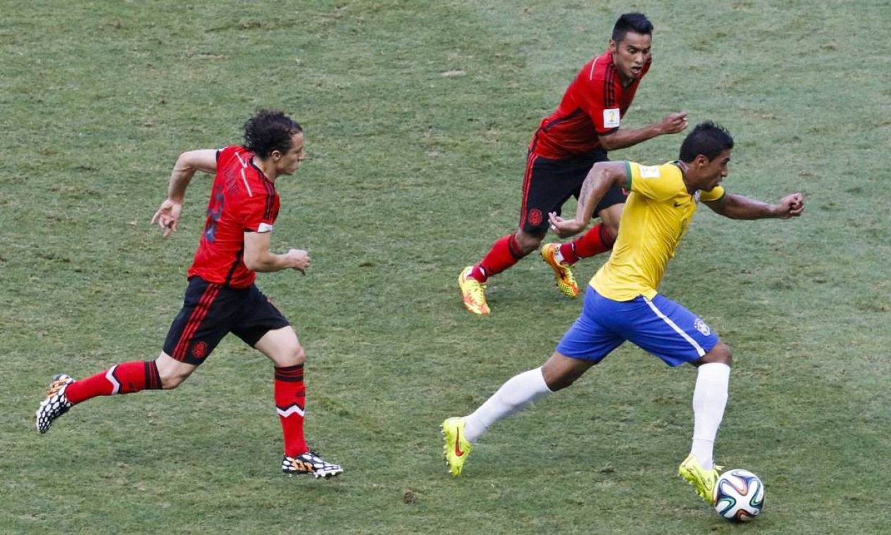 Paulinho arranca com a bola, marcado por dois mexicanos Foto: Guito Moreto / Agência O Globo