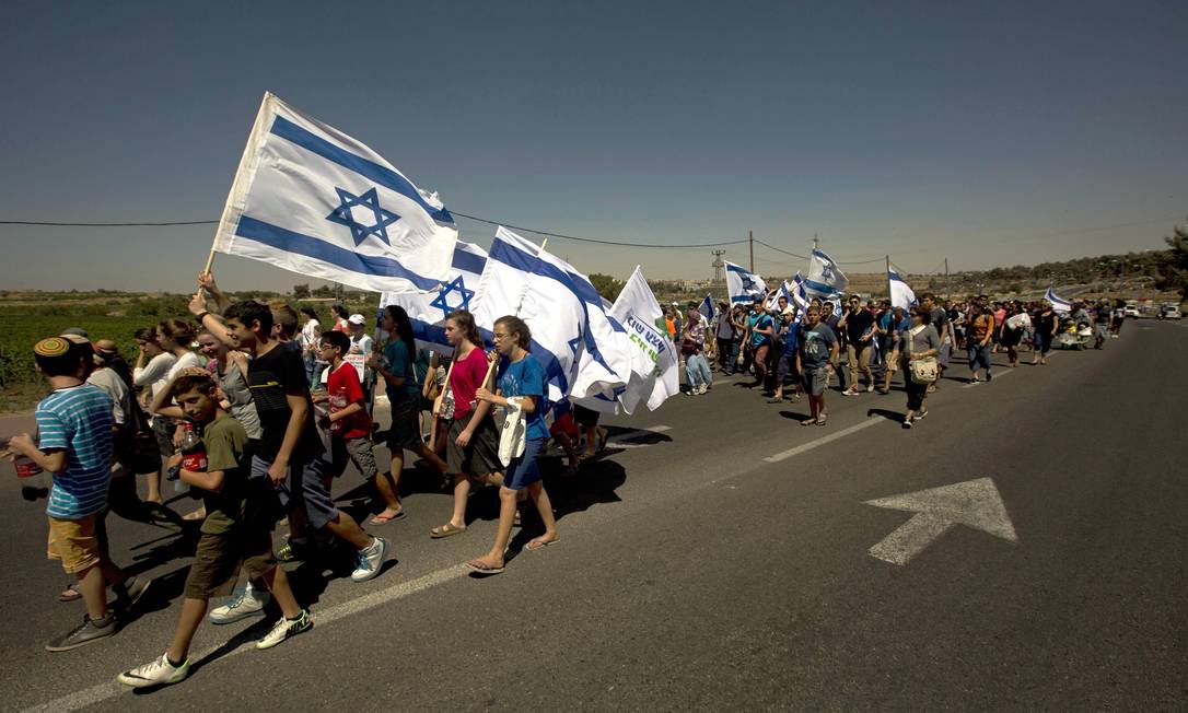 
Israelenses marcham na estrada perto de onde três adolescentes desaparecidos foram sequestrados e mortos na Cisjordânia
Foto:
Sebastian Scheiner
/
AP
