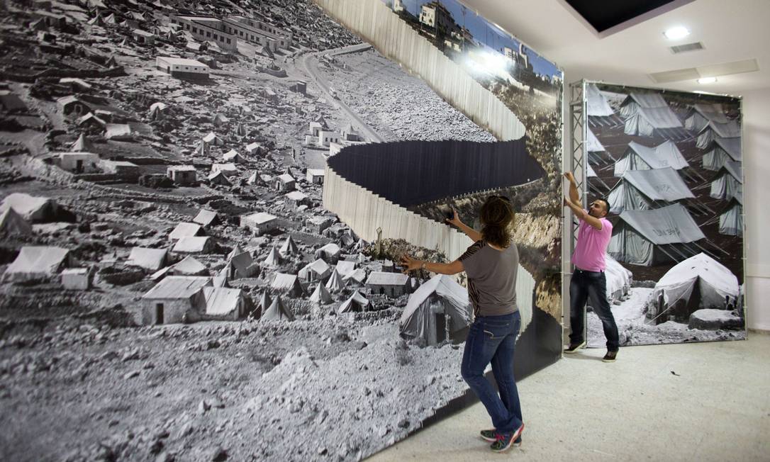 
Em Belém (Israel), exposição em um centro comunitário para refugiados da Palestina superpõe imagens recentes e mais antigas de refugiados palestinos separados por barreira israelense
Foto: AHMAD GHARABLI / AFP