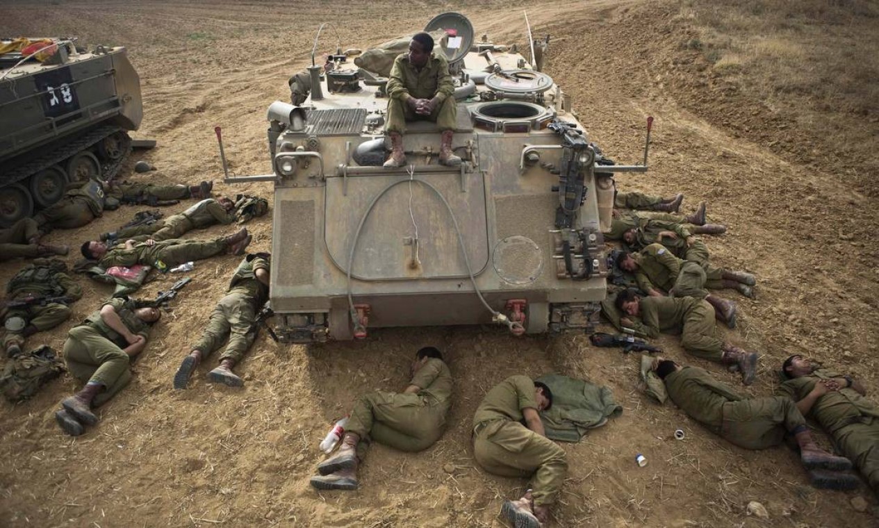 Soldados israelenses dormem no chão ao lado de tanque na fronteira com a Faixa de Gaza Foto: NIR ELIAS / REUTERS