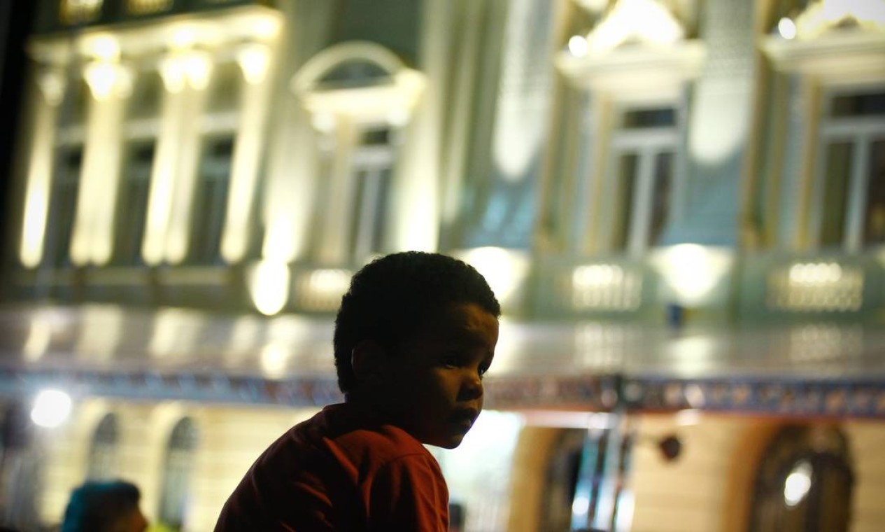 Nas costas de um adulto, menino aguardava a chegada do cortejo Foto: ANDRE COELHO / Agência O Globo