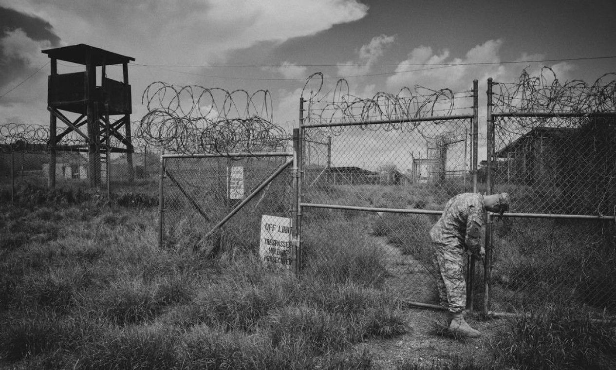Um militar abre o portão da frente do Campo Raio-X para uma visita da imprensa às antigas instalações da base Naval de Guantánamo dos EUA, em Cuba Foto: DAMON WINTER / NYT