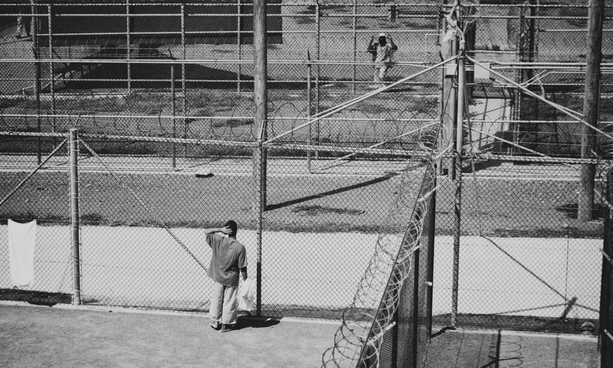 Detentos conversam através de cercas em uma área de recreação ao ar livre, no Campo 6. Mais de 12 anos após o governo Bush enviar os primeiros prisioneiros a Guantánamo, as tensões voltam a crescer em relação se o presidente Obama pode ou não fechar a prisão antes de deixar o cargo Foto: DAMON WINTER / NYT