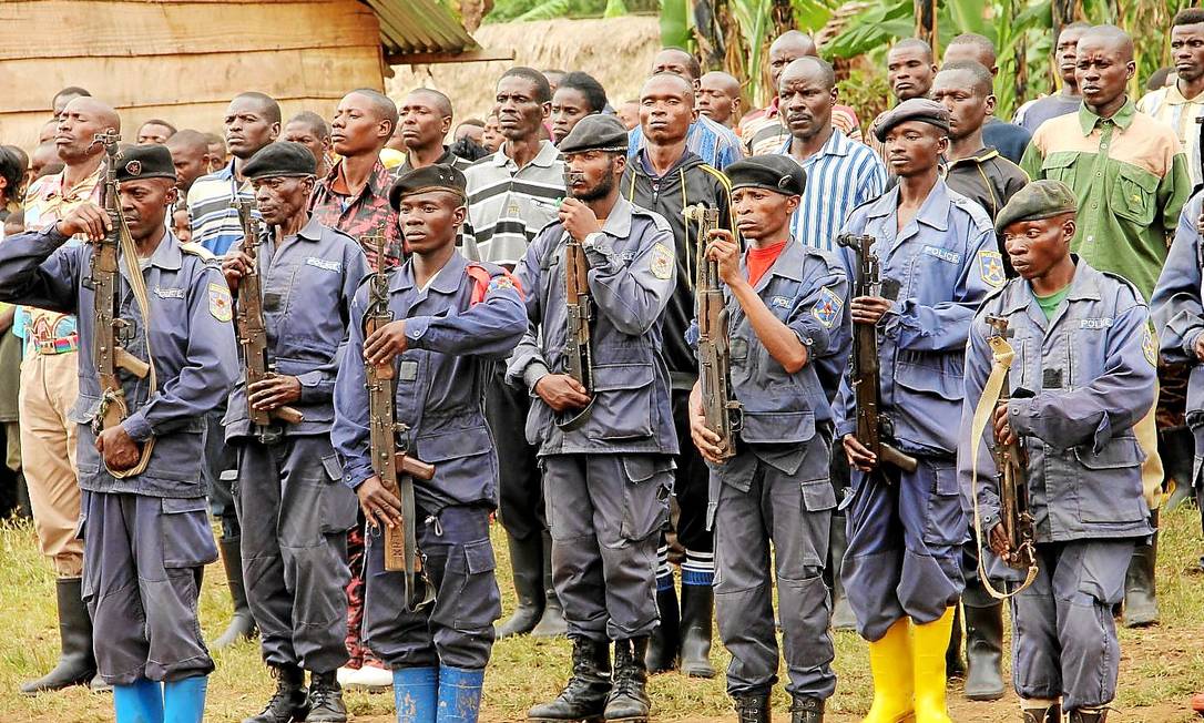 
Uniformizados, policiais congoleses exibem suas armas em frente a guerrilheiros de Ruanda, que se renderam após uma trégua
Foto: NYT/9-6-2014
