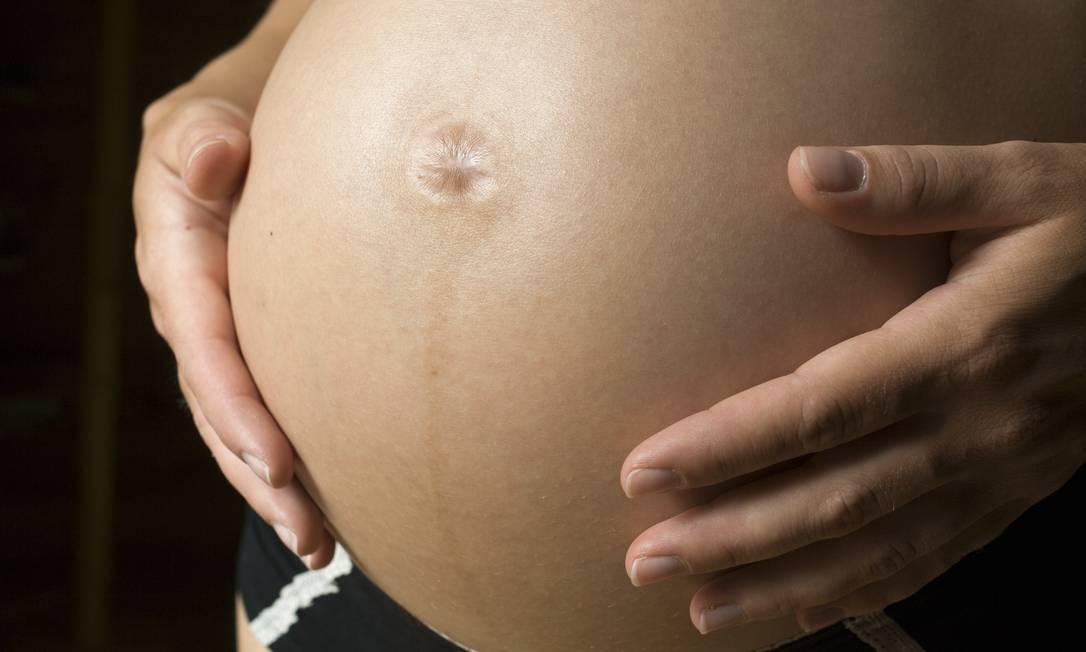 13 Jul 2009 --- Pregnant woman with hand on stomach, mid section, close-up --- Image by © Jenny Gaulitz/Etsa Images/Corbis Foto: Jenny Gaulitz / © Jenny Gaulitz/Etsa Images/Corbis