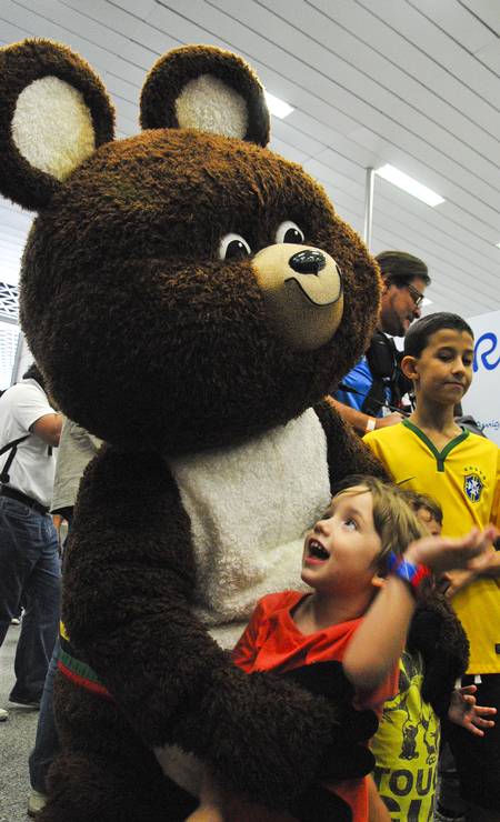 Misha, o mais popular dos mascotes, abraça uma das crianças que estavam no aeroporto e foram correndo ver os mascotes Foto: Alex Ferro / Divulgação
