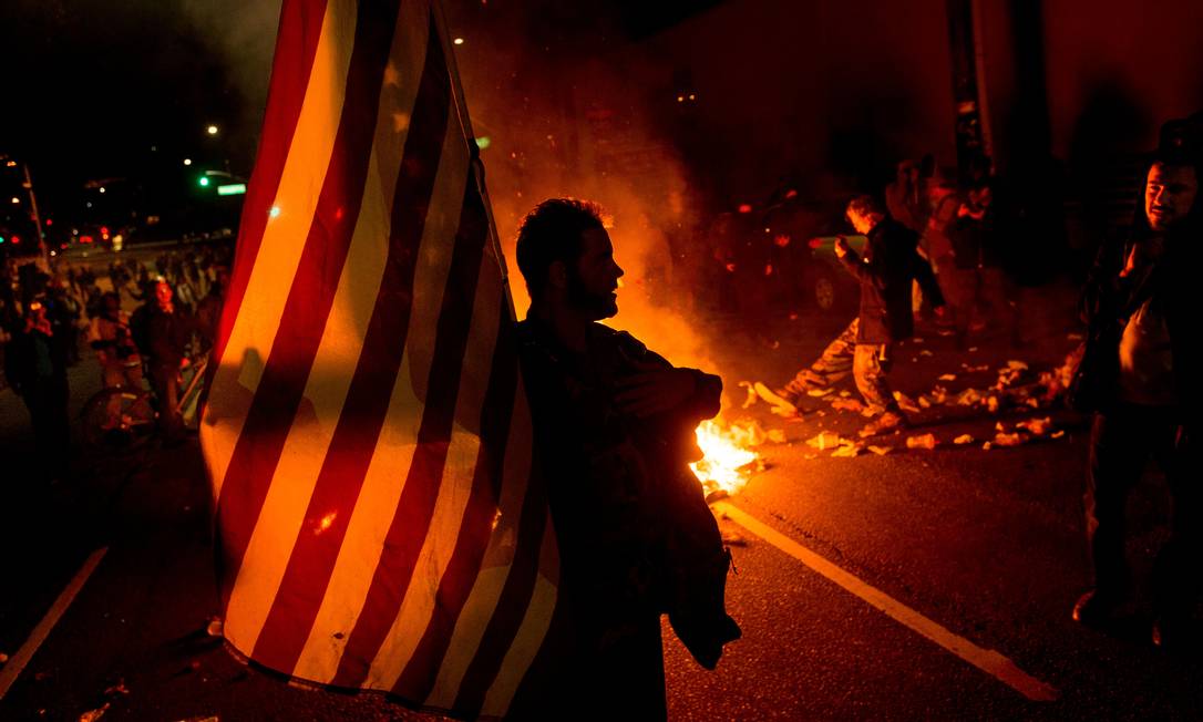 
Manifestante carrega bandeira americana durante protesto em Oakland, na Califórnia
Foto:
Noah Berger
/
AP
