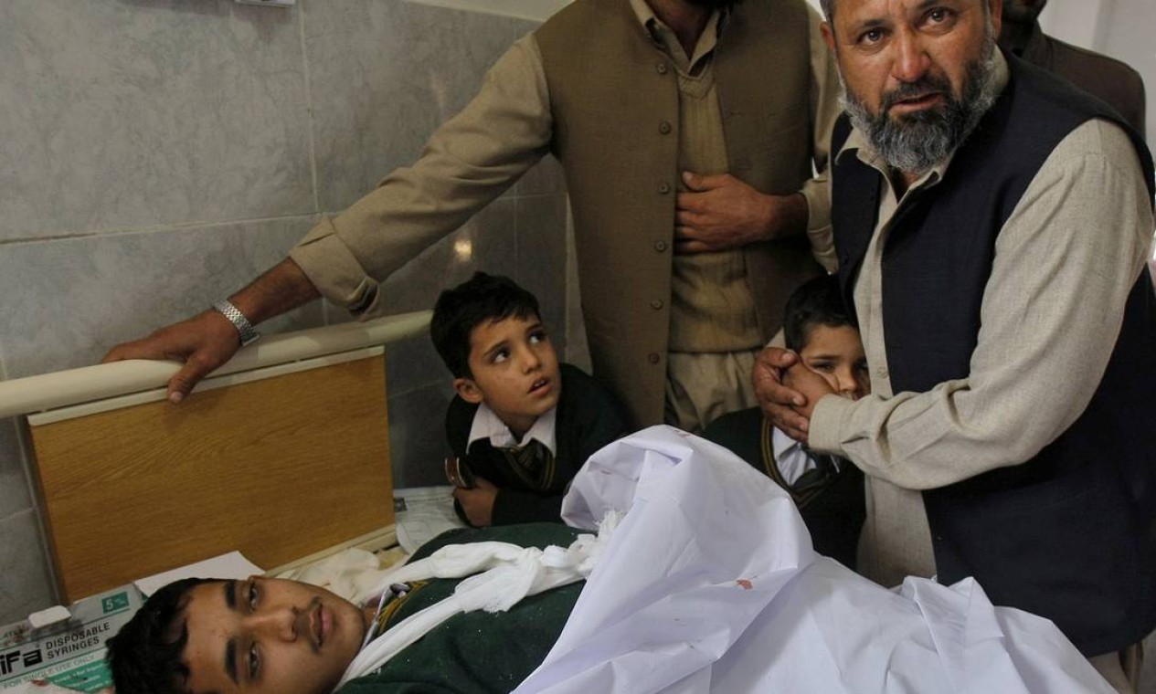 Um paquistanês conforta um aluno no hospital. O premier Nawaz Sharif classificou o episódio de tragédia e decretou três dias de luto nacional Foto: Mohammad Sajjad / AP
