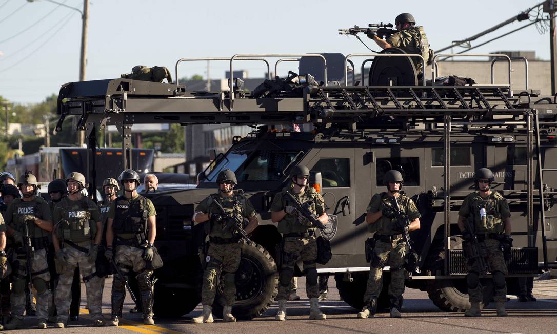 Law enforcement officers, including a sniper perched atop an armored vehicle, watch as demonstrators protest the fatal shooting of Michael Brown, in Ferguson, Mo., Aug. 13, 2014. The police chief of this St. Louis suburb said Wednesday that Brown injured the officer who later fatally shot the unarmed 18 year old ‚Äî though witnesses dispute that such an altercation occurred. (Whitney Curtis/The New York Times) Foto: WHITNEY CURTIS / Agência O Globo