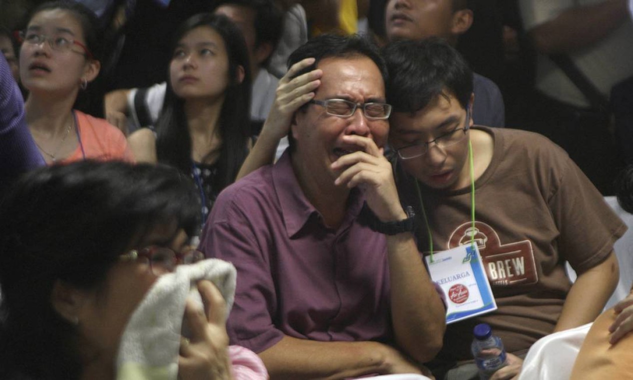 Um homem chora no Aeroporto Internacional de Surabaya, na Indonésia, ao lado de outros parentes de passageiros Foto: Trisnadi / AP